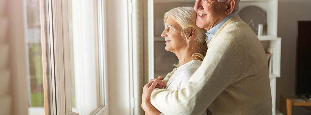 elderly couple looking out their new window replacement in the winter in the Quad Cities.