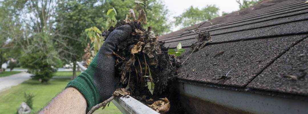 Man cleaning out gutter in winter home improvement