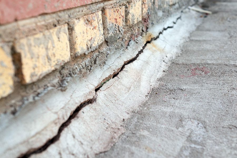 A long and major crack in the foundation of a residential home caused by clogged and leaking gutters.