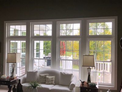 A residential living room with furniture and four white, large floor-to-ceiling vinyl windows that were installed in the Quad Cities area.