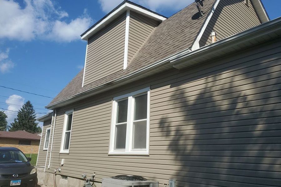 The side view of a home in the Quad Cities that has just had new siding replaced on their home. Light brown siding installation by Mainstream Home Improvements.