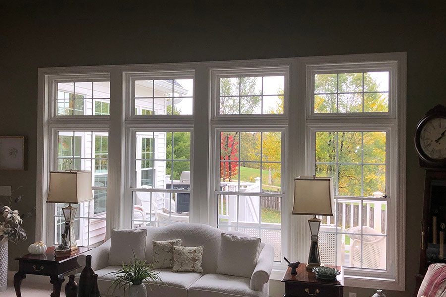 A residential living room with furniture and four white, large floor-to-ceiling vinyl windows that were installed in the Quad Cities area.