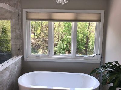 A beautiful residential bathroom with a large freestanding tub and three vinyl windows that were installed by professionals in the Quad Cities area.