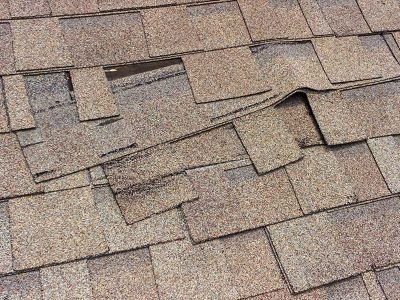 Damaged roof singles on a residential home in Bettendorf, IA that needs to be replaced with GAF shingles by a roofing contractor.