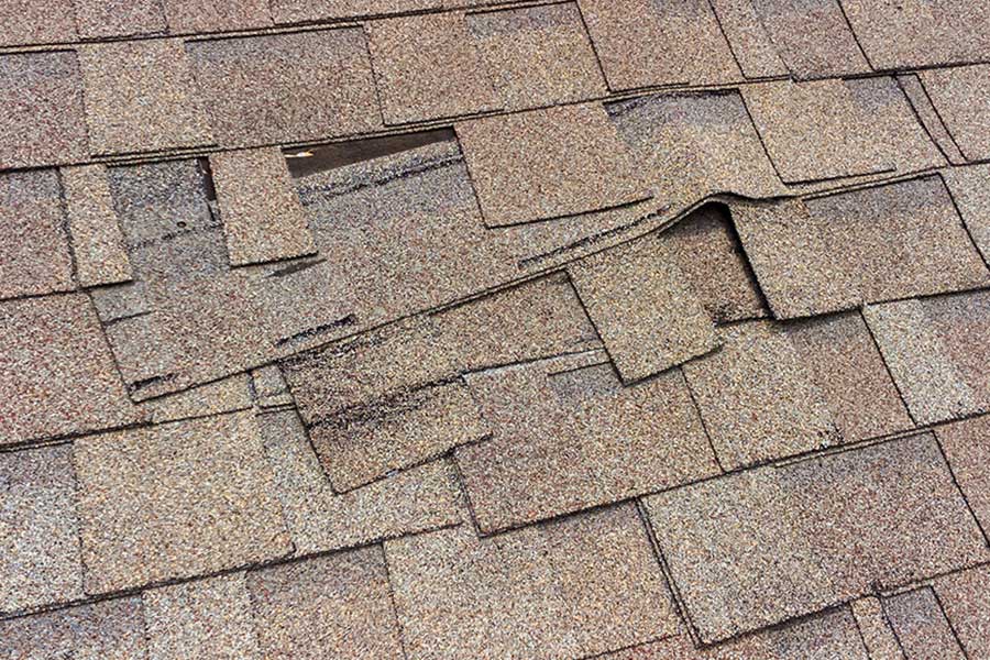 Damaged roof singles on a residential home in Bettendorf, IA that needs to be replaced with GAF shingles by a roofing contractor.