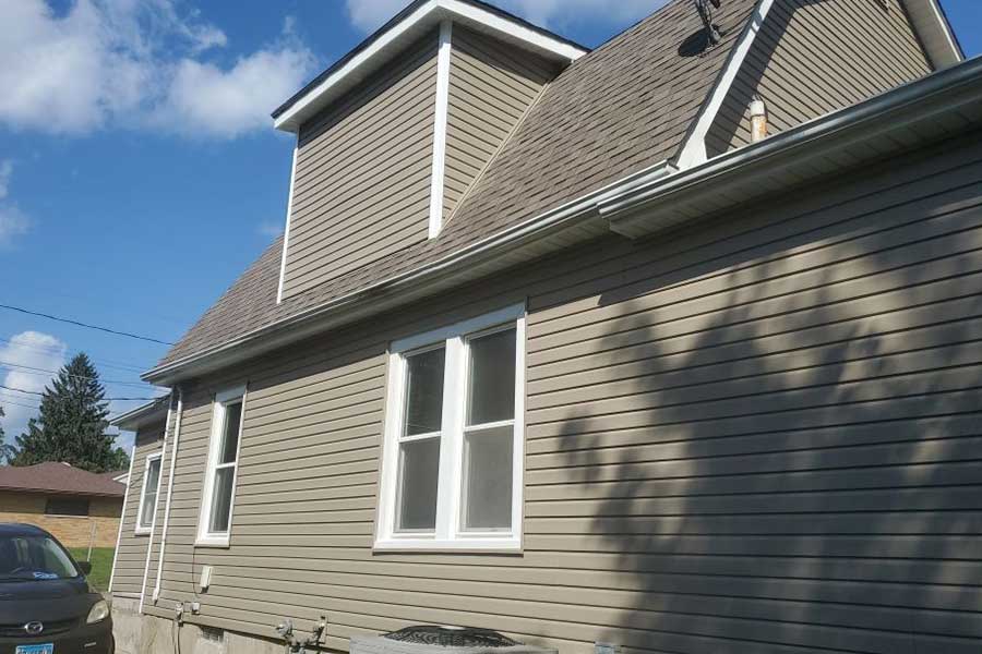 Brand new light brown vinyl siding installed on a two-story residential home in Moline, IL by Mainstream Home Improvement.