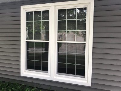 A new double-hung window installed for a residential home in Davenport, IL with a thick white trimming.