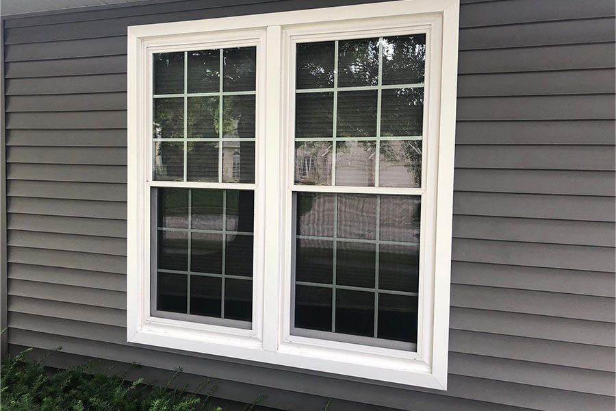 A new double-hung window installed for a residential home in Davenport, IL with a thick white trimming.