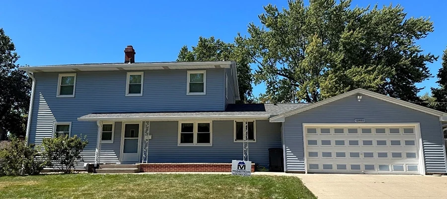 This is a picture of a house with newly installed light blue siding by Mainstream Home Improvement.
