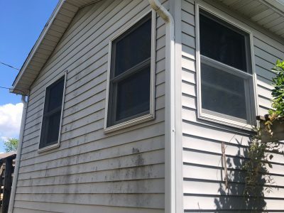 camanche window replacement - exterior side windows of two-story white house, before