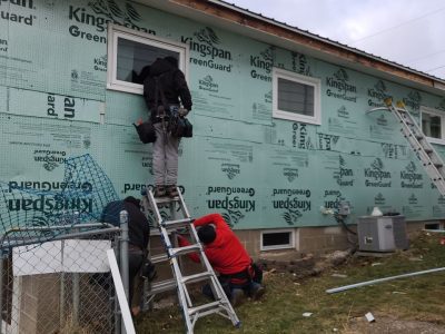 muscatine siding replacement - worker on ladder installing new siding layers, during