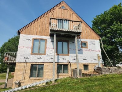 milan siding replacement - back of house with scaffolding, during