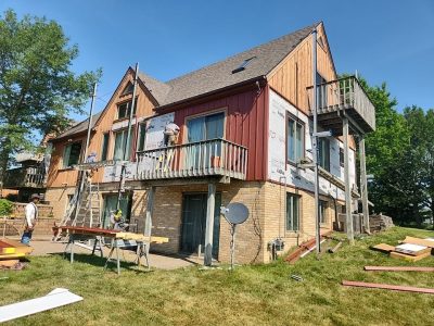 milan siding replacement - corner of house with scaffolding, during