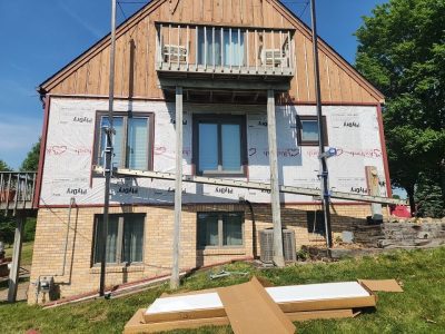 milan siding replacement - back of house with scaffolding, during - 2