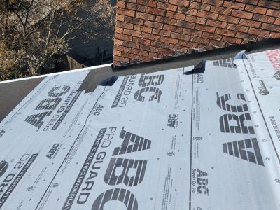 davenport roofing replacement - workers installing new roof layers near chimney, during