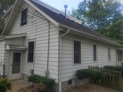 rock island roofing replacement - side corner view of white ranch-style house, before