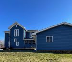 aledo siding replacement - backyard view of tall two-story house with new blue siding, after