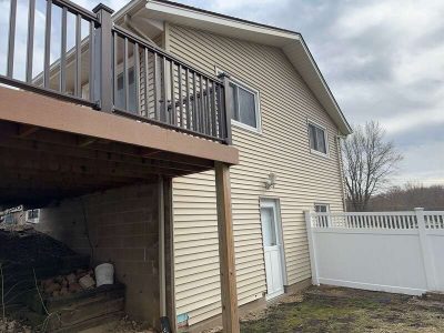taylor ridge siding installation - backyard corner view of tan house with large brown deck, before