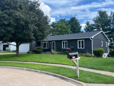clinton siding installation - front/side street view of house with new navy siding, after