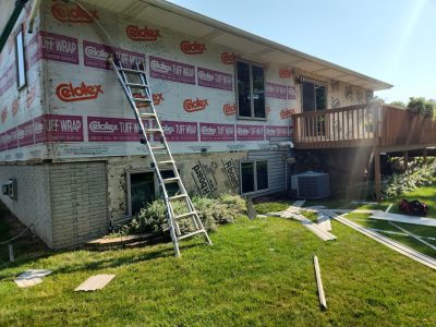clinton siding installation - back of house with new siding layers and ladder, during