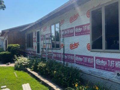 clinton siding installation - side view of front of house with new siding layers, during